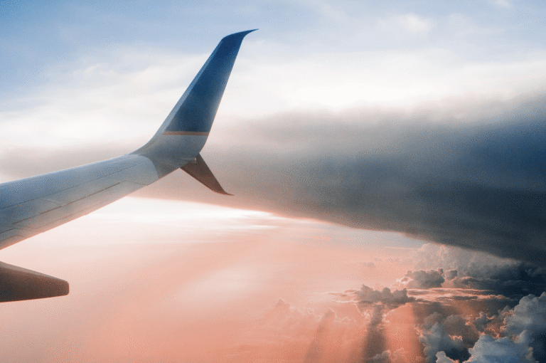 Airplane in the gray clouds against a pink sky